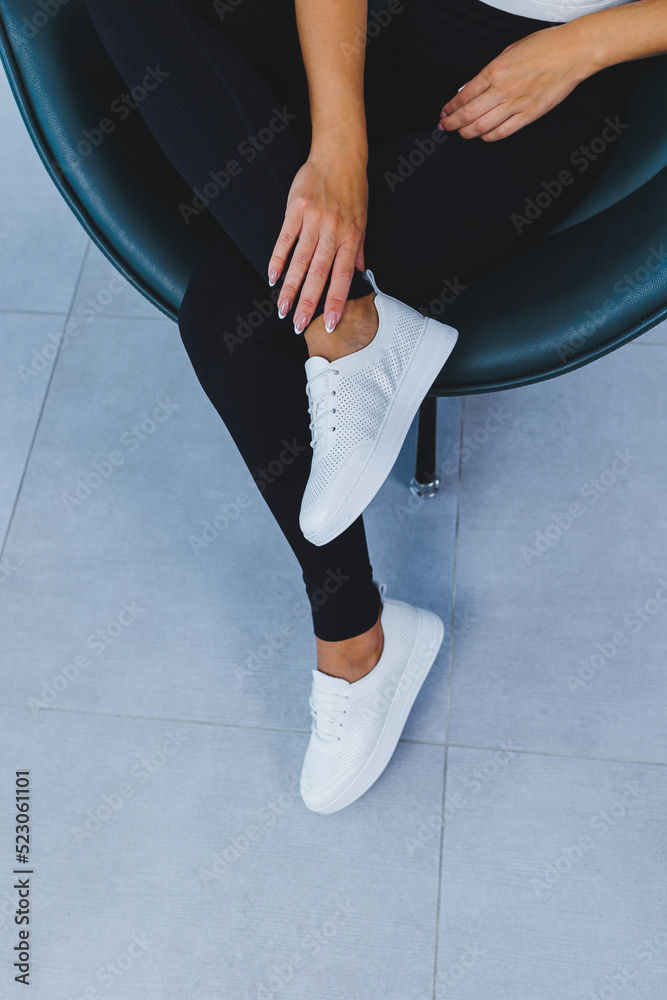 Women's legs close-up in white leather sneakers made from natural leather.Collection of women's summer shoes Women's legs close-up in white leather sneakers made from natural leather.Collection of women's summer shoes