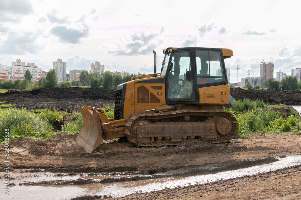 Crawler bulldozer clears the ground with a metal shield. Road construction works. The caterpillar bulldozer is used for layer-by-layer movement of soils. Crawler bulldozer clears the ground with a metal shield. Road construction works. The caterpillar bulldozer is used for layer-by-layer movement of soils.