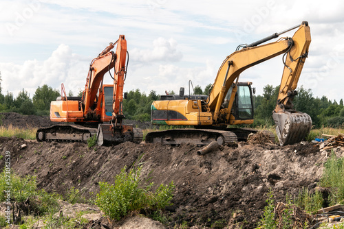 Crawler excavators dig the earth with a bucket. Drainage of swamps. Clearing the construction site. Peat mining. Road construction works.