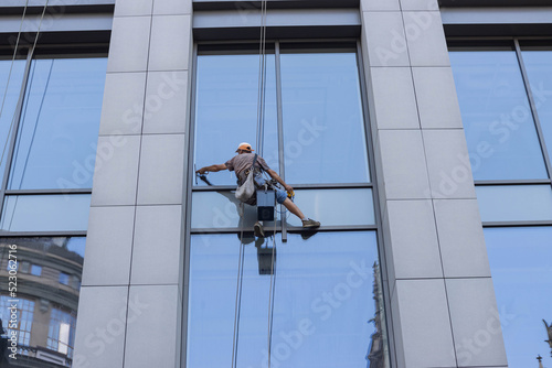 Сlose up worker cleaning mirror in high bilding on sunset