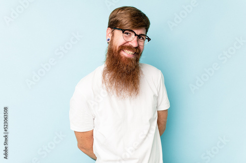 Young caucasian red-haired man isolated on blue background happy, smiling and cheerful. © Asier