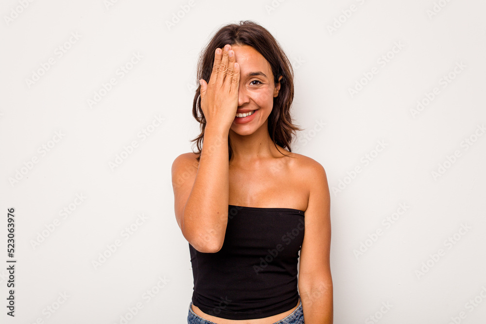 Young hispanic woman isolated on white background having fun covering half of face with palm. Young hispanic woman isolated on white background having fun covering half of face with palm.