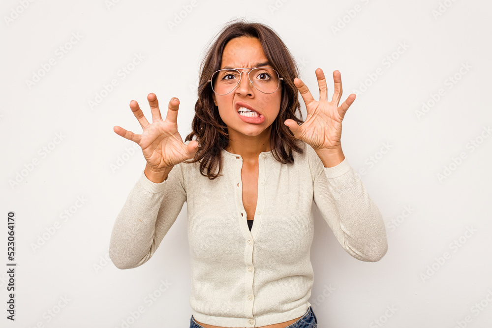 Young hispanic woman isolated on white background showing claws imitating a cat, aggressive gesture. Young hispanic woman isolated on white background showing claws imitating a cat, aggressive gesture.