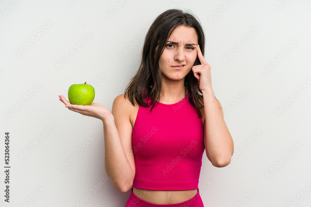 Young caucasian woman holding an apple isolated on white background showing a disappointment gesture with forefinger. Young caucasian woman holding an apple isolated on white background showing a disappointment gesture with forefinger.