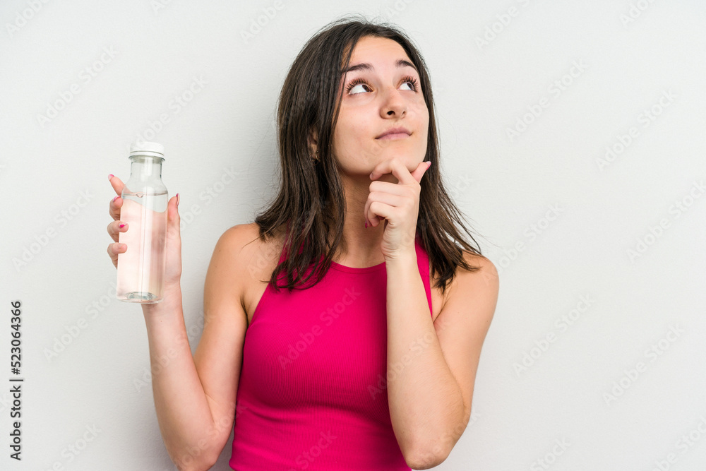 Young caucasian woman holding a bottle of water isolated on white background looking sideways with doubtful and skeptical expression. Young caucasian woman holding a bottle of water isolated on white background looking sideways with doubtful and skeptical expression.