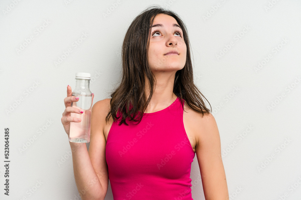 Young caucasian woman holding a bottle of water isolated on white background dreaming of achieving goals and purposes Young caucasian woman holding a bottle of water isolated on white background dreaming of achieving goals and purposes