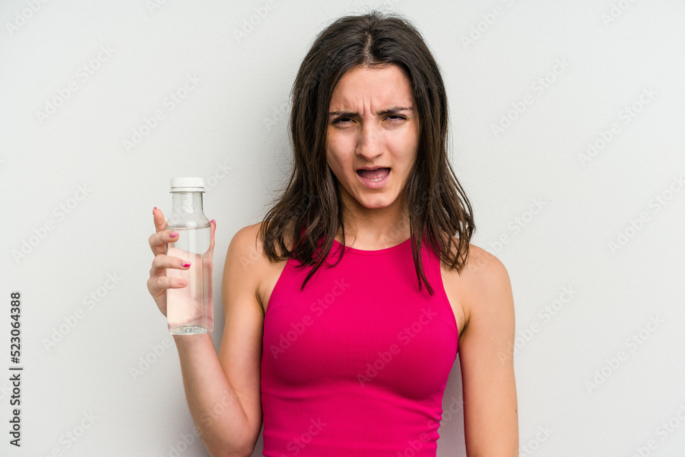 Young caucasian woman holding a bottle of water isolated on white background screaming very angry and aggressive. Young caucasian woman holding a bottle of water isolated on white background screaming very angry and aggressive.