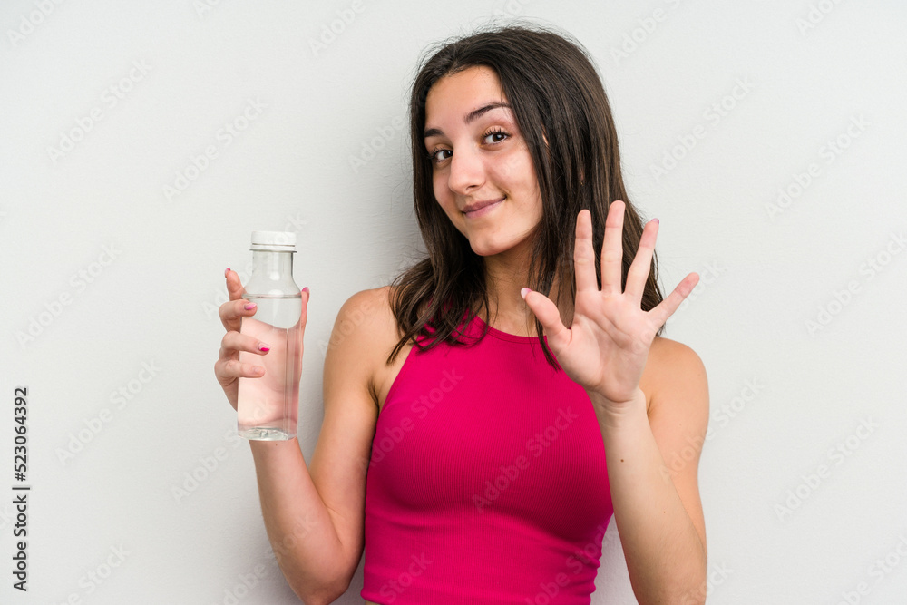 Young caucasian woman holding a bottle of water isolated on white background smiling cheerful showing number five with fingers. Young caucasian woman holding a bottle of water isolated on white background smiling cheerful showing number five with fingers.