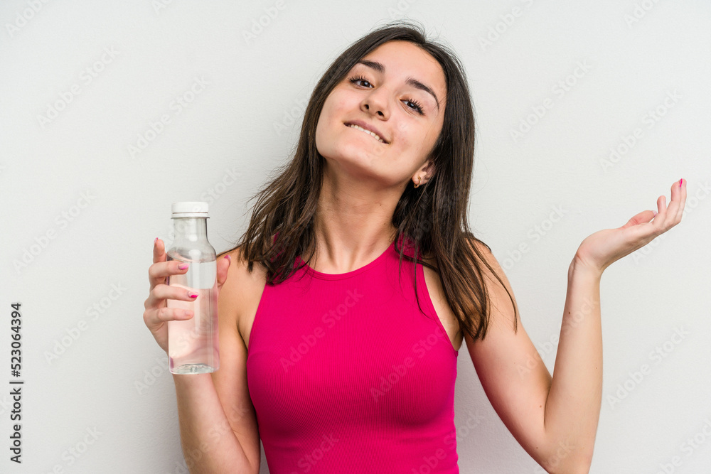 Young caucasian woman holding a bottle of water isolated on white background receiving a pleasant surprise, excited and raising hands. Young caucasian woman holding a bottle of water isolated on white background receiving a pleasant surprise, excited and raising hands.
