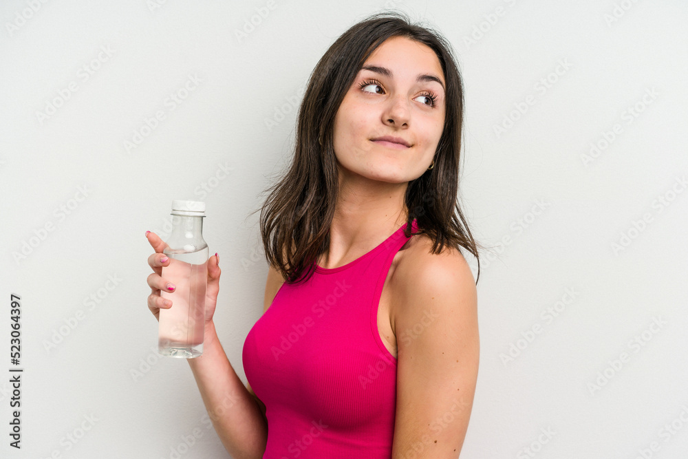 Young caucasian woman holding a bottle of water isolated on white background looks aside smiling, cheerful and pleasant. Young caucasian woman holding a bottle of water isolated on white background looks aside smiling, cheerful and pleasant.
