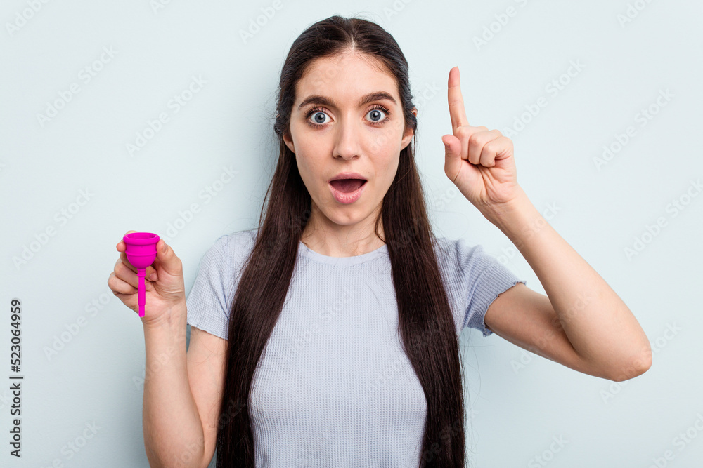 Young caucasian woman holding a sanitary napkin isolated on blue background having an idea, inspiration concept. Young caucasian woman holding a sanitary napkin isolated on blue background having an idea, inspiration concept.
