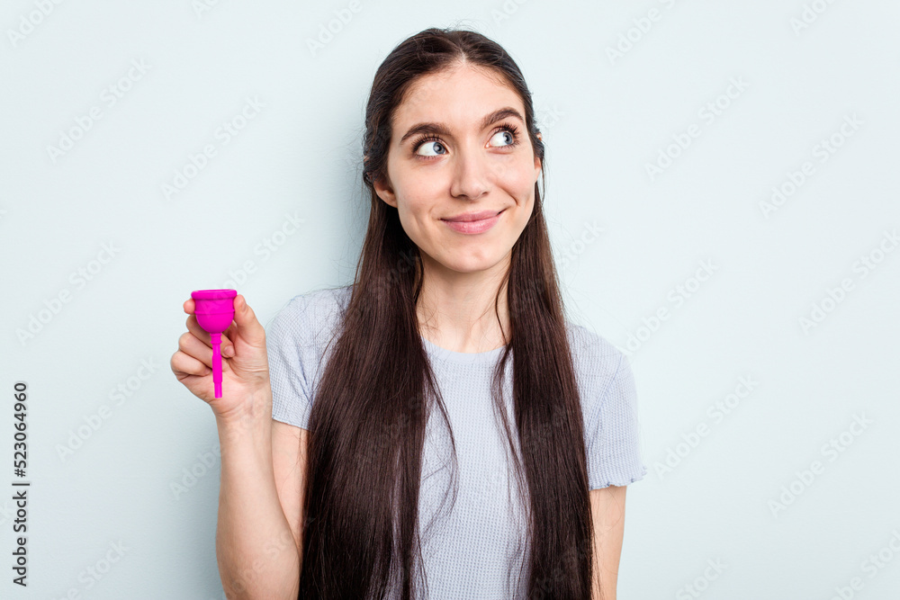 Young caucasian woman holding a sanitary napkin isolated on blue background dreaming of achieving goals and purposes