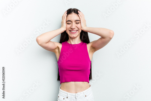 Young caucasian woman isolated on white background laughs joyfully keeping hands on head. Happiness concept.