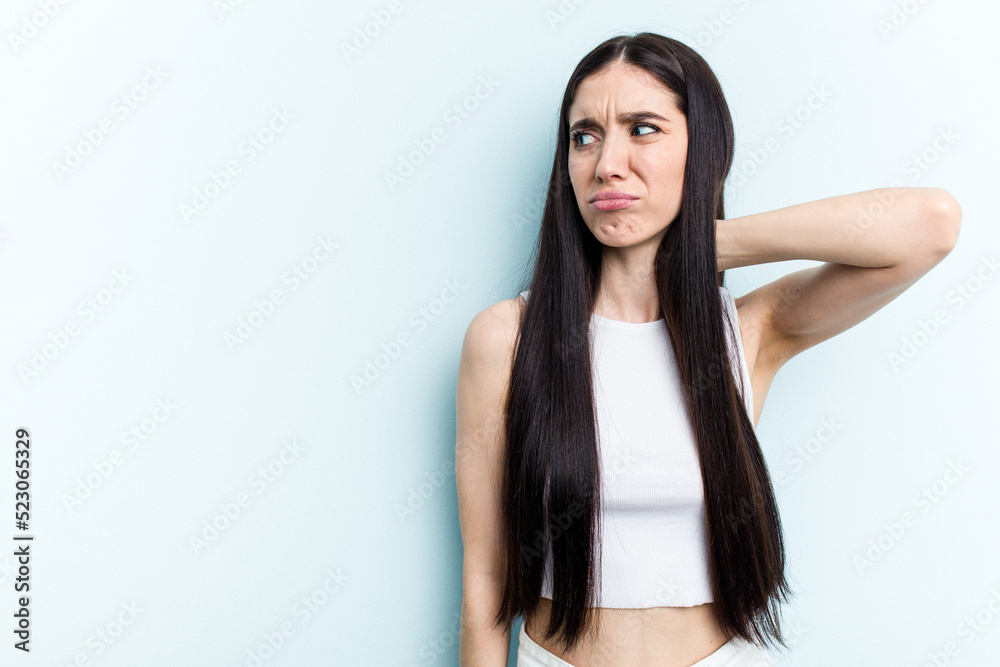 Young caucasian woman isolated on blue background touching back of head, thinking and making a choice. Young caucasian woman isolated on blue background touching back of head, thinking and making a choice.