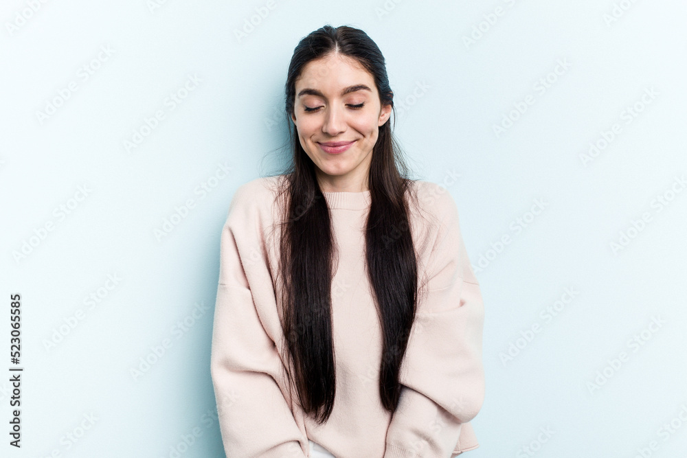 Young caucasian woman isolated on blue background laughs and closes eyes, feels relaxed and happy. Young caucasian woman isolated on blue background laughs and closes eyes, feels relaxed and happy.