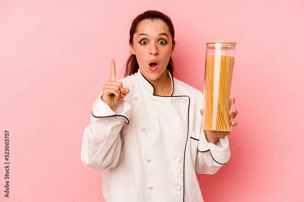 Young chef caucasian woman holding a spaghettis jar isolated on pink background having an idea, inspiration concept. Young chef caucasian woman holding a spaghettis jar isolated on pink background having an idea, inspiration concept.