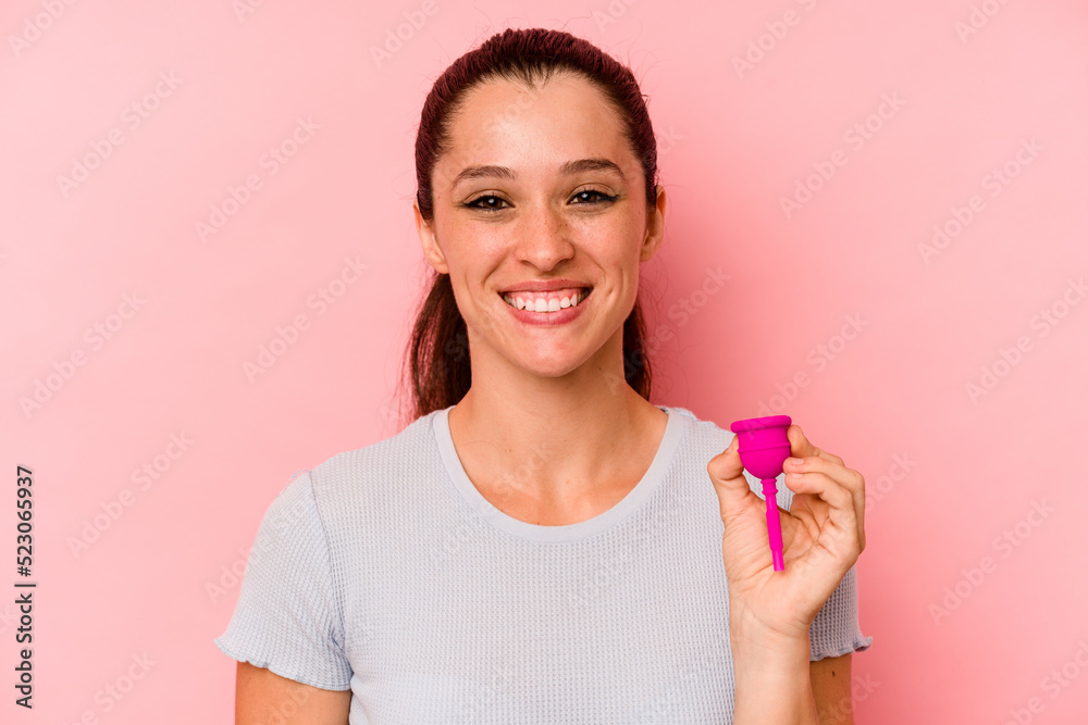 Young caucasian woman holding a menstrual cup isolated on pink background happy, smiling and cheerful. Young caucasian woman holding a menstrual cup isolated on pink background happy, smiling and cheerful.