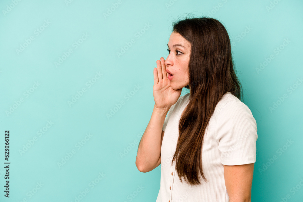 Young caucasian woman isolated on blue background is saying a secret hot braking news and looking aside Young caucasian woman isolated on blue background is saying a secret hot braking news and looking aside