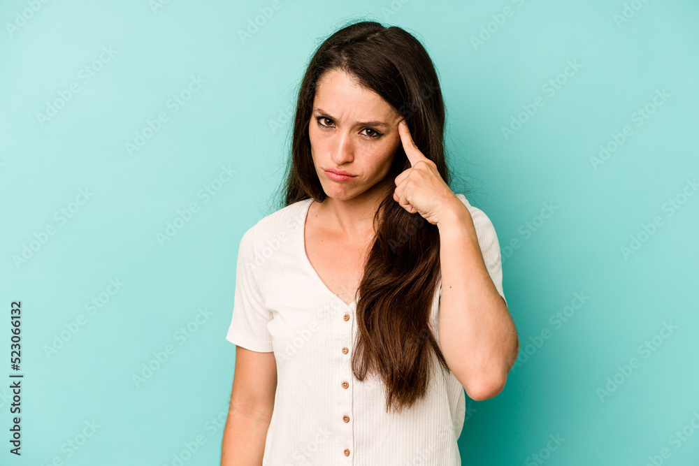 Young caucasian woman isolated on blue background pointing temple with finger, thinking, focused on a task. Young caucasian woman isolated on blue background pointing temple with finger, thinking, focused on a task.