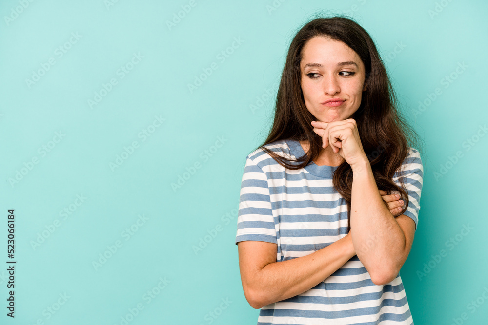 Young caucasian woman isolated on blue background looking sideways with doubtful and skeptical expression. Young caucasian woman isolated on blue background looking sideways with doubtful and skeptical expression.