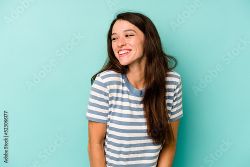 Young caucasian woman isolated on blue background laughs and closes eyes, feels relaxed and happy.