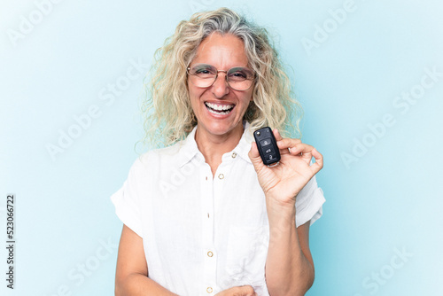 Middle age caucasian woman holding a car keys isolated on blue background laughing and having fun.