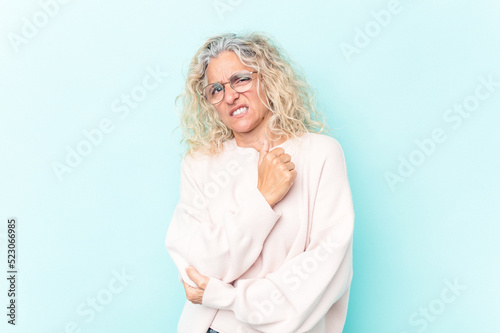 Middle age caucasian woman isolated on blue background massaging elbow, suffering after a bad movement.