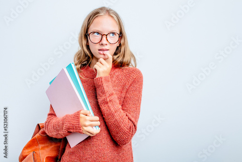 Caucasian teen student woman isolated on blue background relaxed thinking about something looking at a copy space.