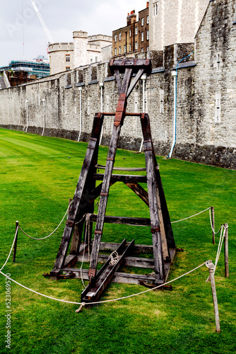 on a green lawn near the walls of the Tower of London, an old catapult is presented photo