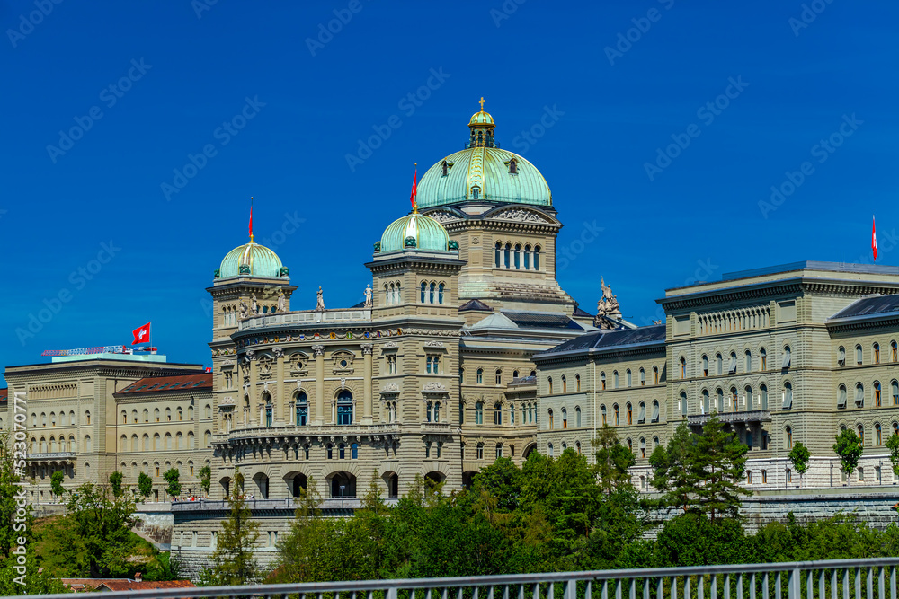 BERN, SWITZERLAND - August 2nd 2022: View on The Federal Palace of Switzerland (Bundeshaus) from the Kirchenfeld Bridge.