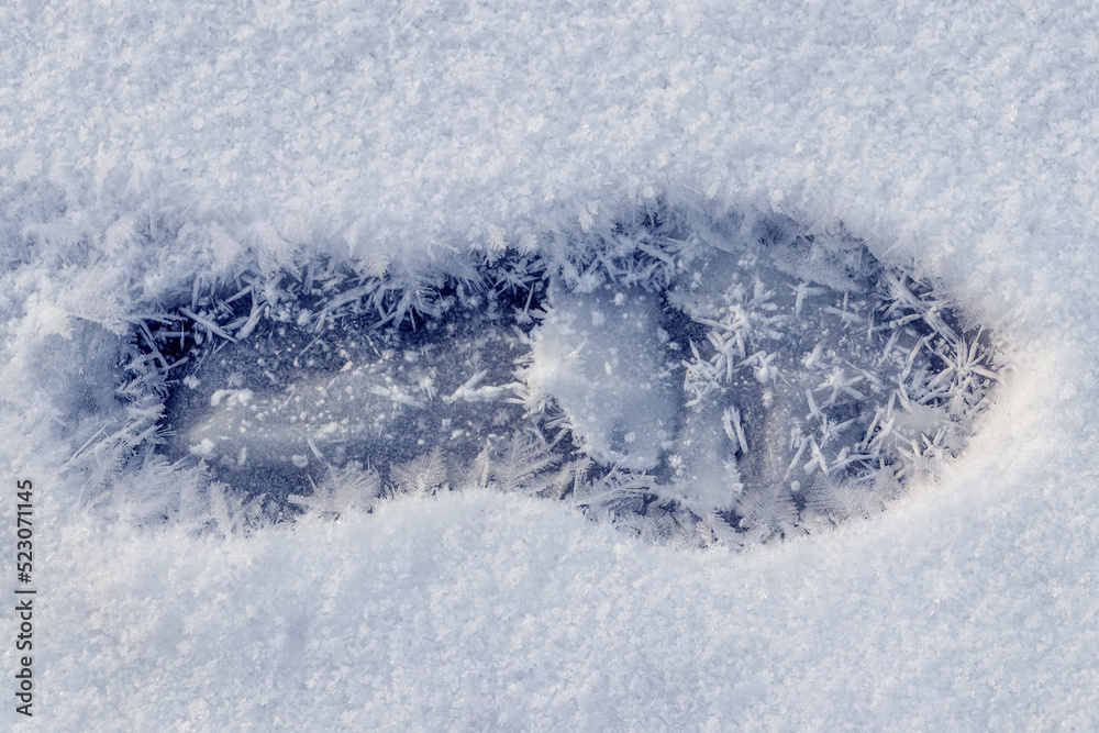 A human footprint in the snow and large snowflakes