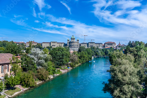 BERN, SWITZERLAND - August 2nd 2022: The Federal Palace of Switzerland (Bundeshaus) and people enjoying river life to beat the summer heat.