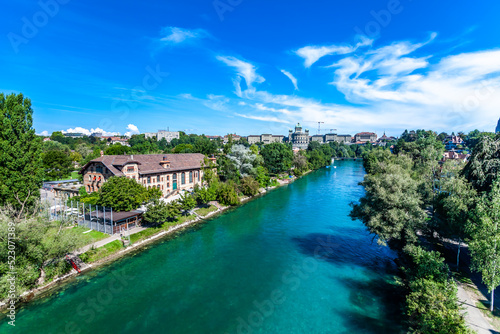BERN, SWITZERLAND - August 2nd 2022: The Federal Palace of Switzerland (Bundeshaus) and people enjoying river life to beat the summer heat. © cubrick