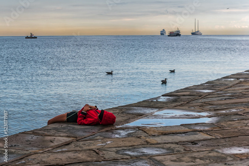 boy in red lying at the mole audace in trieste, italy, romantic mood in the dusk
