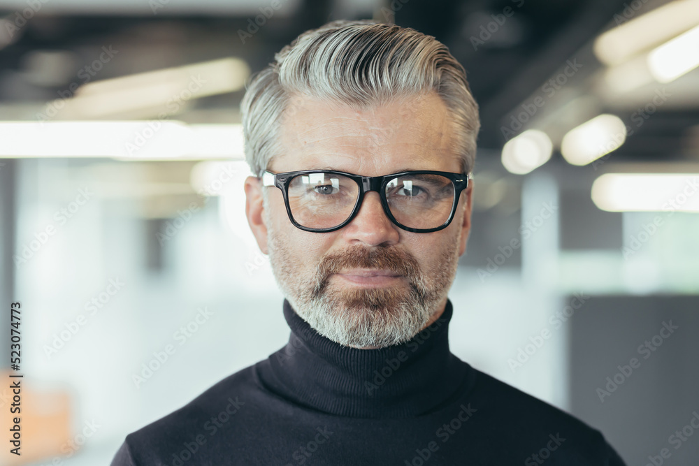 Fototapeta premium Close up photo portrait of successful senior and experienced businessman, man in glasses looking at camera, serious investor banker working in office at work