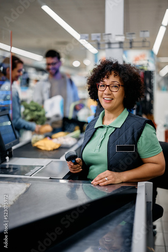 Portrait of happy cashier working in supermarket and looking at camera. photo