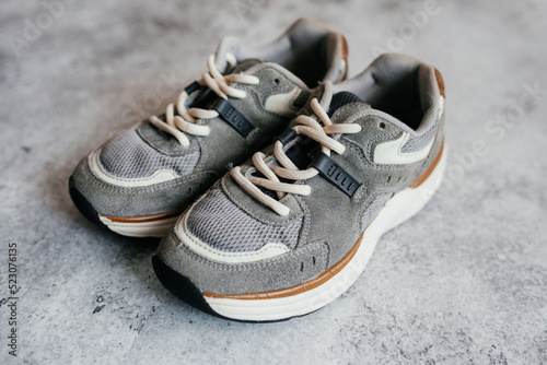 Stylish sports sneakers in gray, boys' casual shoes, isolated on a gray background. Modern, casual footwear.