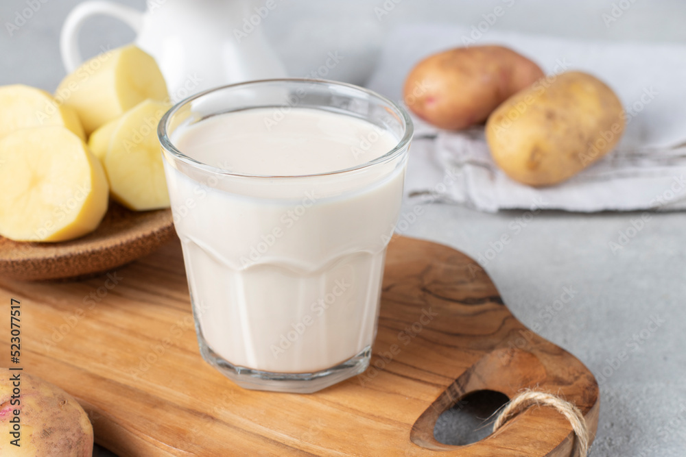 Vegan potato milk in glass and potato in plate on wooden board. Plant based milk replacer and lactose free Vegan potato milk in glass and potato in plate on wooden board. Plant based milk replacer and lactose free