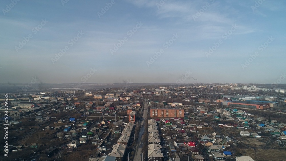 Panorama of polar city in Russia. Low-rise buildings against backdrop of smoking chimneys of industrial enterprises