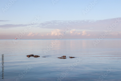 calm ocean landscape with rocks and reflection of clouds