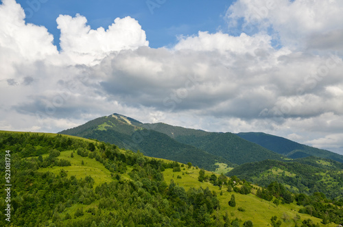 Green slopes of mountains overgrown with forest and Mount Strymba against a cloudy sky near the village of Kolochava, Transcarpathia, Carpathians, Ukraine
