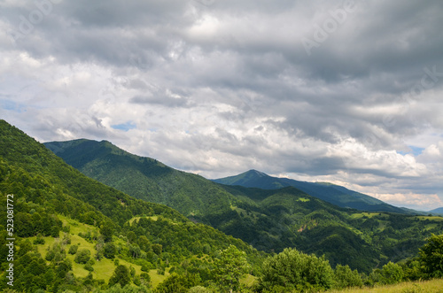 Green slopes of mountains overgrown with forest and Mount Strymba against a cloudy sky near the village of Kolochava  Transcarpathia  Carpathians  Ukraine