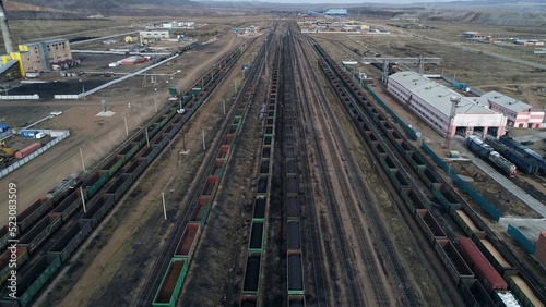 Industrial railroad cars stand in coal port during loading of raw materials. Aerial view