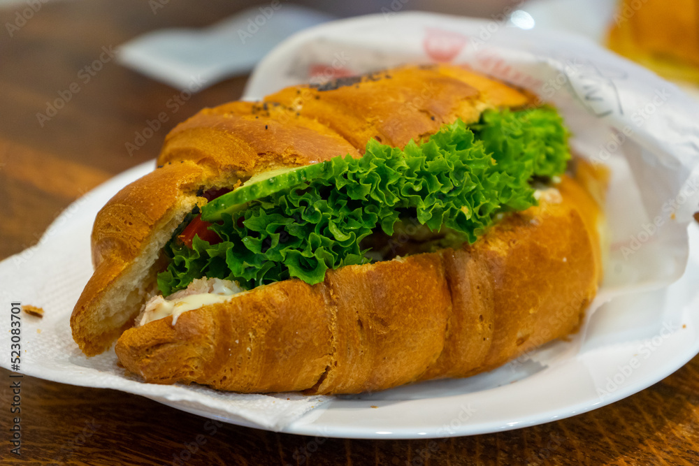 Croissant sandwich with cream cheese, meat and vegetables on a white plate. Concept of healthy breakfast Croissant sandwich with cream cheese, meat and vegetables on a white plate. Concept of healthy breakfast