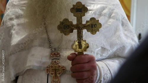 The priest holds the cross in his hand, standing in front of the parishioners photo