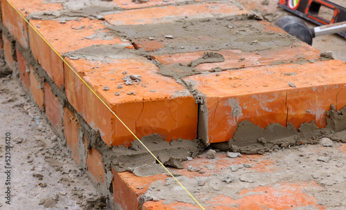 initial rows of brickwork. the initial stage of building a house. masonry of orange ceramic bricks.