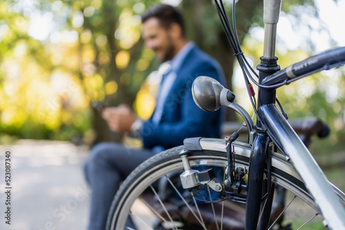 Close up of part of bicycle. men on phone in background. selective focus.