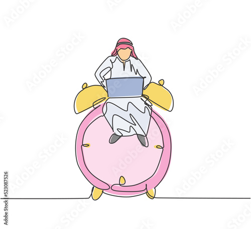Single continuous line drawing young Arab business man sitting on big analog alarm clock and typing on laptop. Business discipline metaphor concept. One line draw graphic design vector illustration.