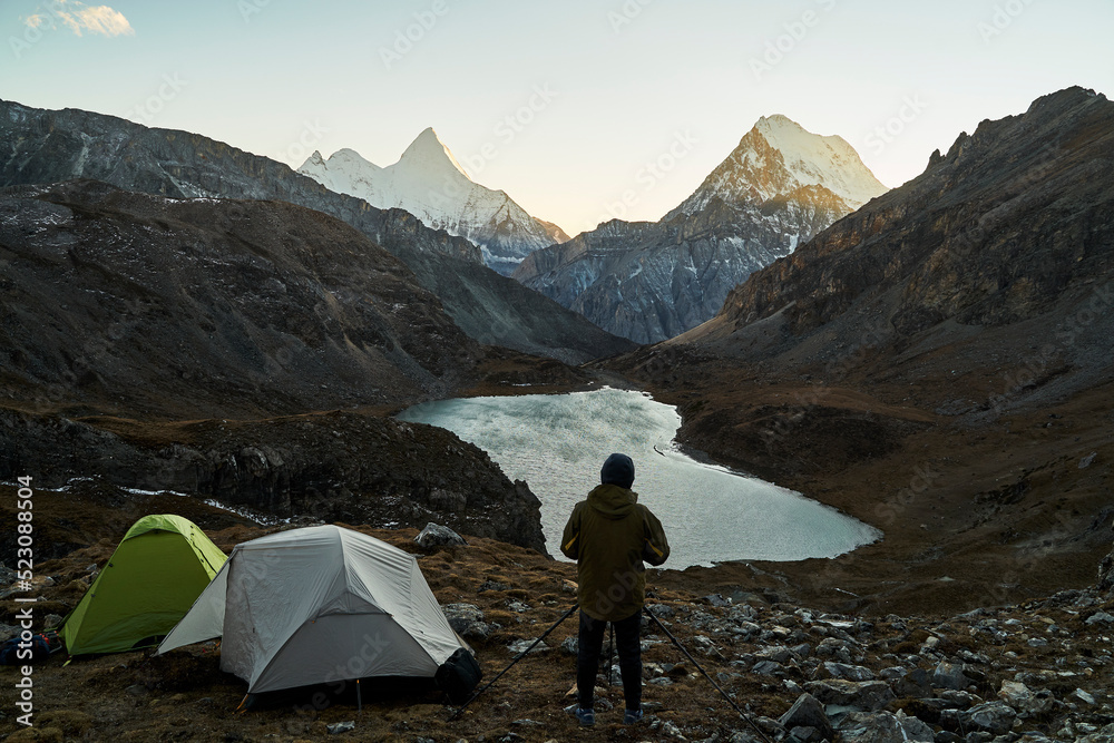 Fototapeta premium asian photographer taking a photo of mountain and lake in yading national park