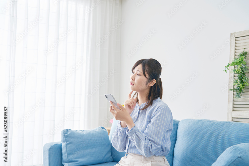 自宅でスマホを持って困る女性 自宅でスマホを持って困る女性